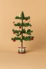 The Maileg Cozy Christmas Corner features a small Christmas tree adorned with red ornaments and white candles, set in a round decorative base against a plain beige background—an ideal addition to your collection of Maileg dollhouse accessories.