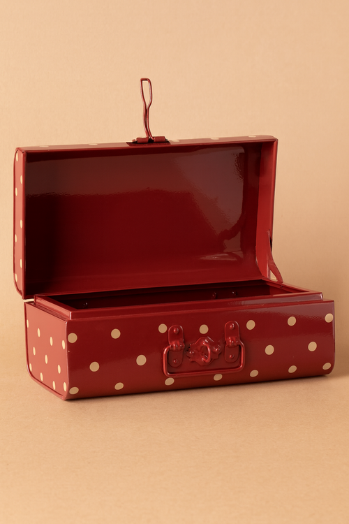 The Maileg Storage Suitcase - Red with Dots, a small vintage-style case from the interior collection, sits open on a beige surface, showing its empty, glossy red metal interior with white polka dots.