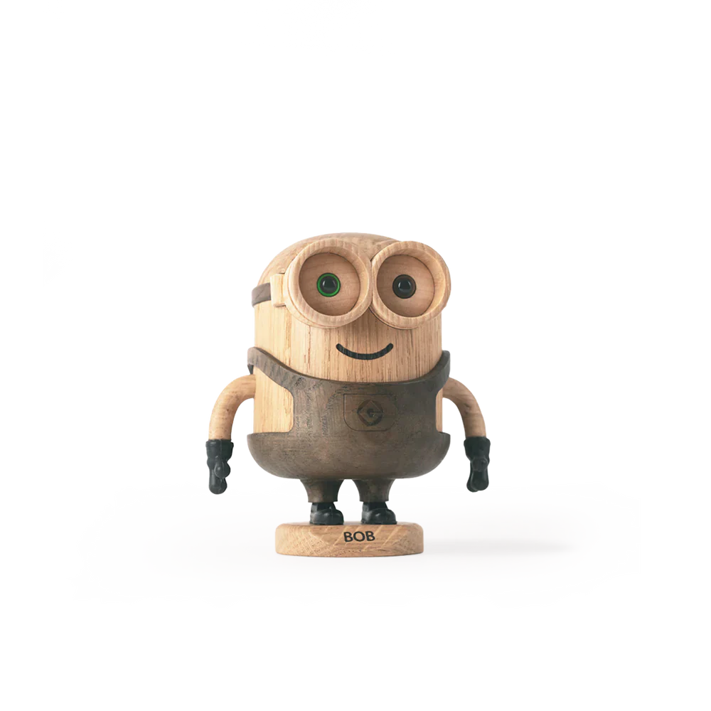 A whimsical wooden robot toy named Boyhood Minion Bob, with round green eyes and metal limbs, stands against a white background with black horizontal stripes.
