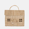 The Olli Ella Casa Bag is a charming, hand-woven rattan basket shaped like a little house, featuring a top handle, hinged roof lid, arched door with knob, and front window patterns.