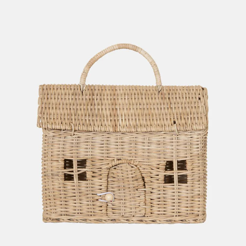 The Olli Ella Casa Bag is a charming, hand-woven rattan basket shaped like a little house, featuring a top handle, hinged roof lid, arched door with knob, and front window patterns.