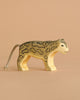 A Handmade Holzwald Snow Leopard with painted spots and a short yarn tail stands on a light brown surface against a matching background, showcasing the charm of sustainable toys.