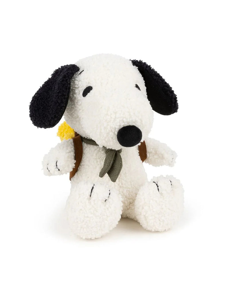 Plush Peanuts Snoopy with Woodstock in Backpack: Stuffed Snoopy dog plush toy sits upright, wears a green scarf and brown backpack holding a yellow sleeping bag, with Woodstock inside, against a white background.