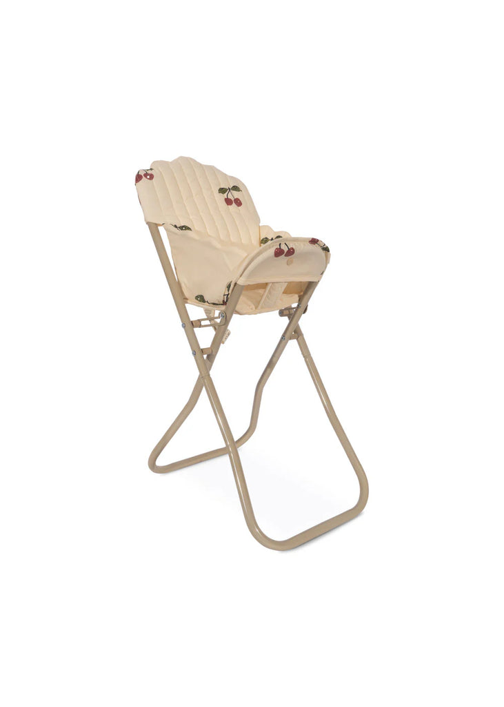 The Konges Sloejd High Chair - Cherry Glitter is a beige folding chair with a cushioned seat and backrest, decorated with charming cherry prints, making it an ideal accessory for dolls. Its straightforward metal frame ensures portability and convenience, and it includes a detachable seat for easy storage and adjustment.