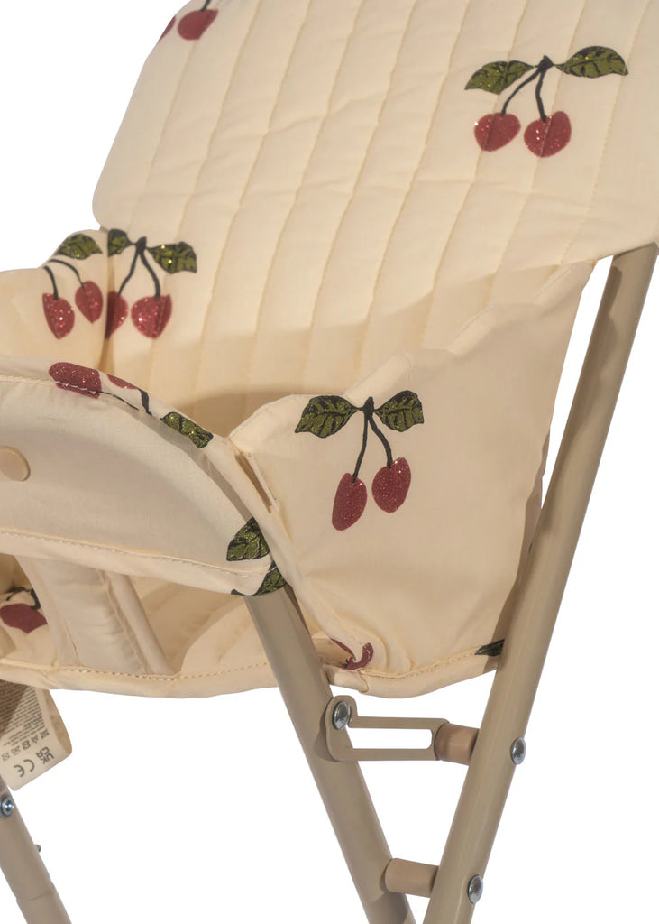 Here's a revised version of the sentence using the given product data:

A close-up of the Konges Sloejd High Chair - Cherry Glitter, showcasing its beige foldable design with a cushioned seat and backrest adorned in a cherry pattern. This high chair is perfect as a doll accessory, featuring a metal frame and intricate fabric stitching.