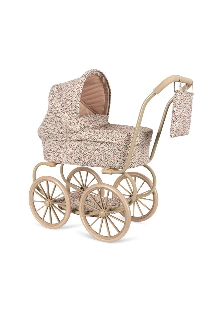 Introducing the Konges Sloejd Mini Doll Pram - Milk Tank, a vintage-style baby stroller featuring quilted fabric with elegant beige upholstery and a subtle floral pattern. It comes with a high canopy, large wheels, and a matching detachable bag hanging from its curved handle. Additionally, it includes a cushioned storage basket for added convenience.