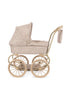 The Konges Sloejd Mini Doll Pram - Milk Tank features a vintage aesthetic with a quilted floral-patterned fabric, complemented by large beige wheels and a matching handlebar. It includes an extended hood and a small cushioned storage basket hanging from the handle, all adorned in the same charming floral design.