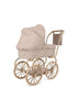 Introducing the Konges Sloejd Mini Doll Pram - Milk Tank: a charming baby stroller with large wheels and a floral-patterned quilted fabric cover, featuring a beige and brown color scheme. This delightful pram includes a matching canopy and a cushioned storage basket on the handle, evoking the essence of vintage-style doll prams.