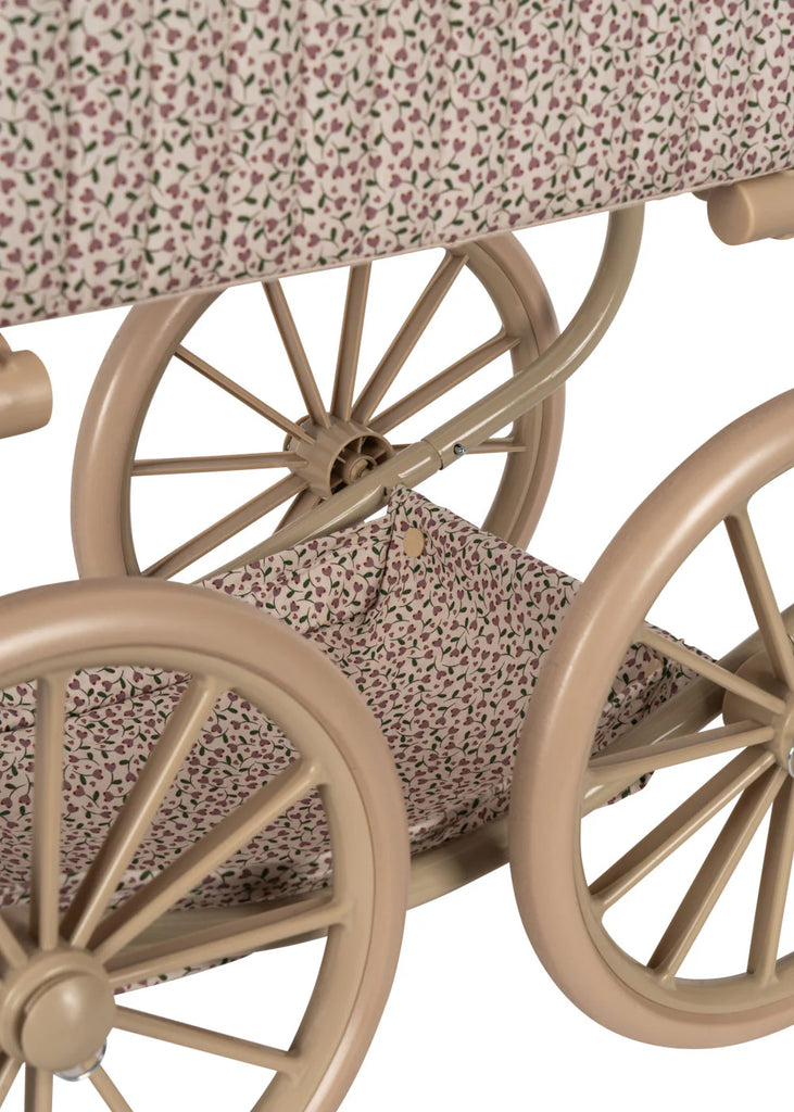 Close-up of the Konges Sloejd Mini Doll Pram - Milk Tank with beige wheels. The quilted fabric displays a floral pattern featuring small leaves and flowers in muted tones. This charming stroller includes a cushioned storage basket underneath, lined with the same delightful patterned fabric.