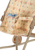 A detailed view of the Konges Sloejd Doll Stroller - Fleur Decor reveals its empty design, characterized by a beige metal frame and double wheels. The stroller features an elegant floral pattern adorned with a blue bow and includes removable fabric for effortless cleaning.