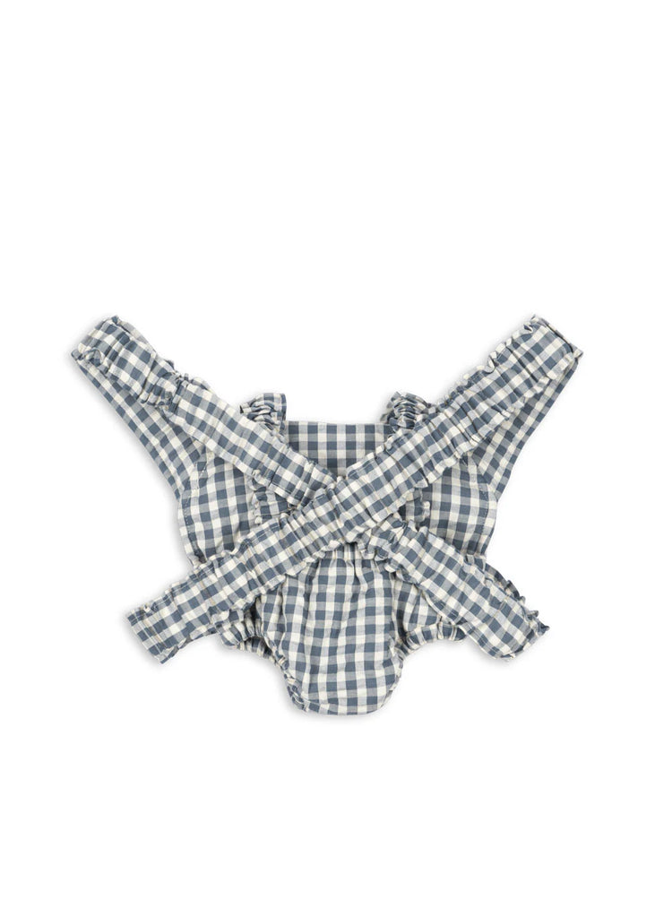 Blue and white gingham baby romper with ruffled edges and crossed straps, laid flat on white—perfect to pair with the Konges Sloejd Doll Carrier in Blue Checkers for adorable, matching playtime moments.