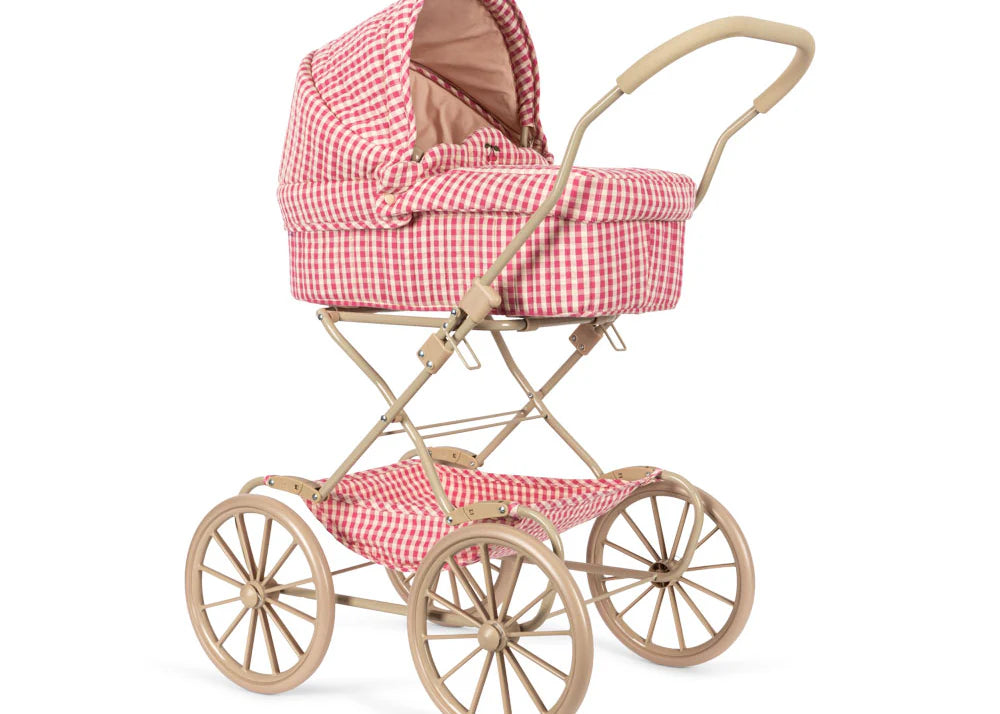 The Konges Sloejd Doll Pram - Bubblegum Check features a vintage beige frame, large spoked wheels, and pink and white checkered quilted fabric with a cozy padded mattress, displayed on a crisp white background.