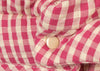 Close-up of the Konges Sloejd Doll Pram - Bubblegum Check shows quilted, pink and white checkered fabric with a cream snap button, featuring padded texture with visible folds and stitched seams.