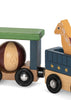 A close-up of the Konges Sloejd Wooden Animal Train, crafted from beechwood, showcases magnetic train cars: one carrying a brown and tan ball under a green roof, and the other featuring a yellow horse figure in a blue wagon decorated with stars.