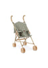 The Konges Sloejd Doll Stroller - Smoke Pine Checker features a lightweight, foldable beige frame, green checkered seat, curved handles, and double wheels on each leg, shown against a white background.