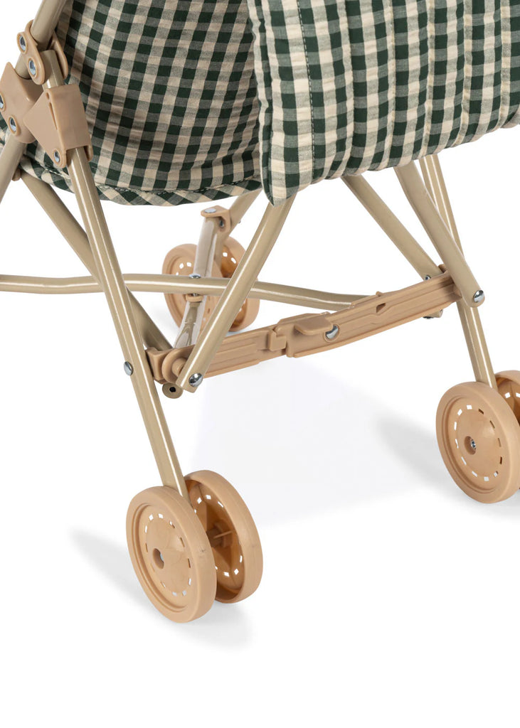 Close-up of the lower part of the Konges Sloejd Doll Stroller - Smoke Pine Checker, featuring beige plastic double wheels, a sturdy frame, and a green and white checkered fabric seat.