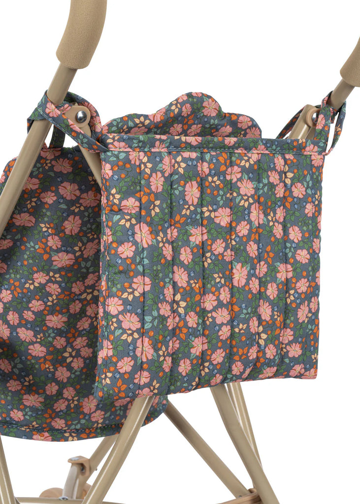 A close-up of the Konges Sloejd Doll Stroller - Kyoto shows its floral-patterned fabric bag with pink, orange, and white flowers attached to the side of a beige frame.