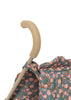 Close-up of the Konges Sloejd Doll Stroller - Kyoto handle with a beige foam grip. The stroller fabric has a vibrant floral pattern in pink, orange, and white on a blue background. White backdrop.