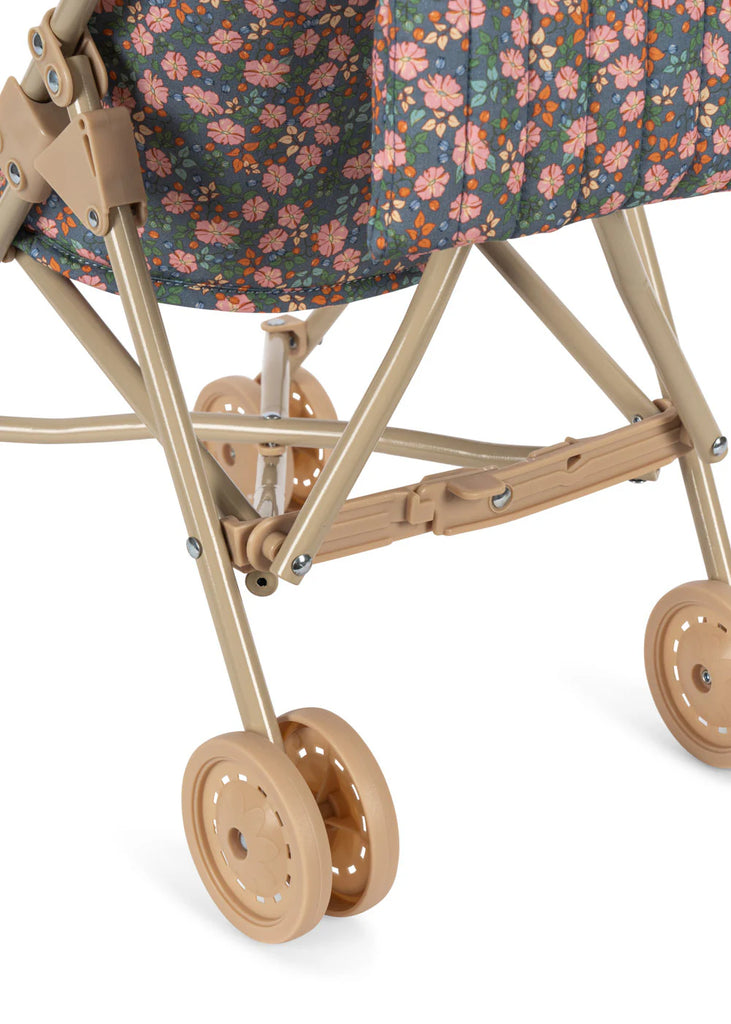 Close-up of the lower part of the Konges Sloejd Doll Stroller - Kyoto in beige, featuring double wheels and a floral fabric seat with pink and orange flowers on a dark background.