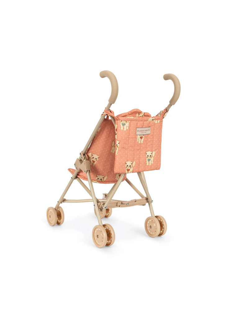 The Konges Sloejd Doll Stroller - Ciao Miao Rose is a compact stroller with beige double wheels and handles, showcasing a peach-colored fabric seat adorned with bear faces and a subtle pattern. The stroller is shown from the back and side views.