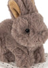 A close-up of the Konges Sloejd Take Care of Me Animals - Bunny shows its fluffy brown fur, black eyes, and tan inner ears as it sits on a white textured surface. This adorable plush bunny seems to say, “take care of me,” inviting everyone to cuddle and cherish this charming mini toy animal.
