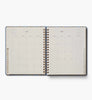 An open 2027 Schoolhouse 17-Month Academic Hardcover Spiral Planner displays a monthly calendar for June, with dates arranged in a grid on the left page and a lined notes section on the right. Colorful tabs for other months are visible along the right edge, making navigation easy through this spacious planner, which provides both weekly and monthly planning options.