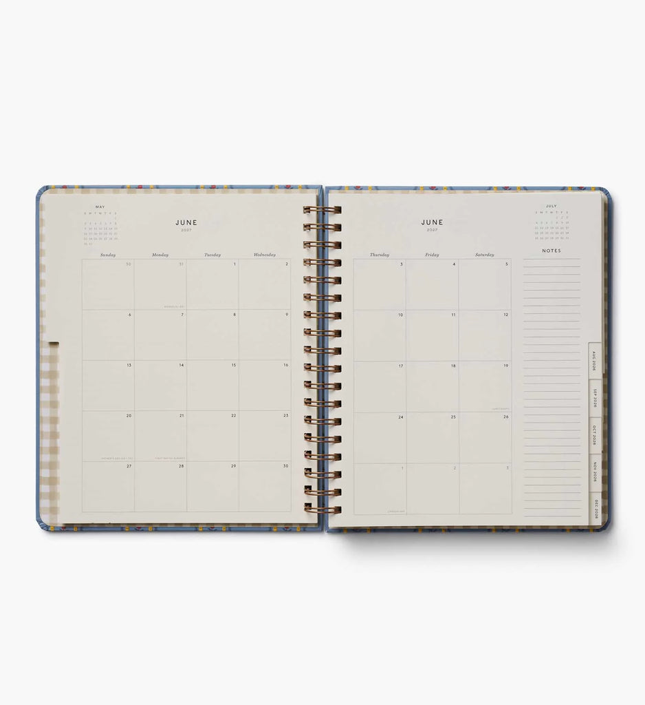 An open 2027 Schoolhouse 17-Month Academic Hardcover Spiral Planner displays a monthly calendar for June, with dates arranged in a grid on the left page and a lined notes section on the right. Colorful tabs for other months are visible along the right edge, making navigation easy through this spacious planner, which provides both weekly and monthly planning options.