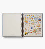 An open 2027 Schoolhouse 17-Month Academic Hardcover Spiral Planner displays a blank lined page on the left and a vibrant sheet of stickers featuring flowers, animals, food, and reminder labels on the right—perfect for personalizing your planner experience.