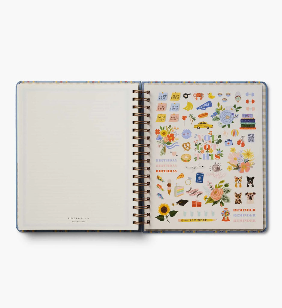 An open 2027 Schoolhouse 17-Month Academic Hardcover Spiral Planner displays a blank lined page on the left and a vibrant sheet of stickers featuring flowers, animals, food, and reminder labels on the right—perfect for personalizing your planner experience.