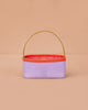The Sticky Lemon Treasure Bag - Dewy Lilac is a small rectangular bag in lavender PU leather with a yellow handle, orange rim, and red-and-white checkered interior, shown against a peach background.
