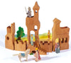 Ostheimer Tower with Stairs with various connected structures, including towers and walls. Handcrafted wooden toys feature a horse, a king, knights with weapons, and other characters. Trees and grassy landscape in the background enhance the medieval theme, promoting imaginative play with sustainable materials.