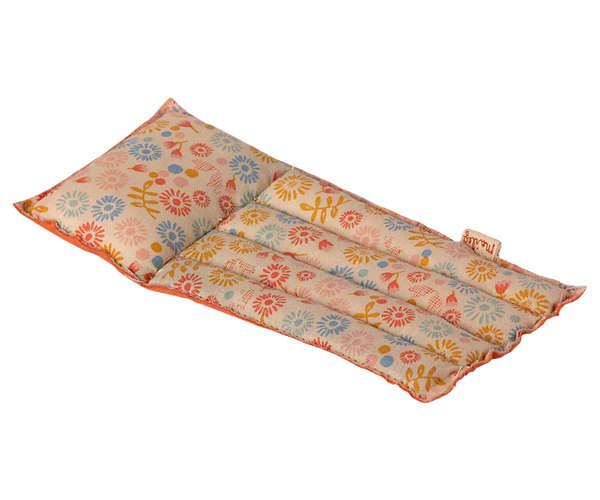 The Maileg Beach Float, Mouse - Flower is a rectangular heating pad adorned with a floral pattern, primarily featuring red, yellow, and blue flowers on a light background. This pad is segmented into three columns and made from durable raft-like fabric to ensure longevity. It also features a label on one edge.