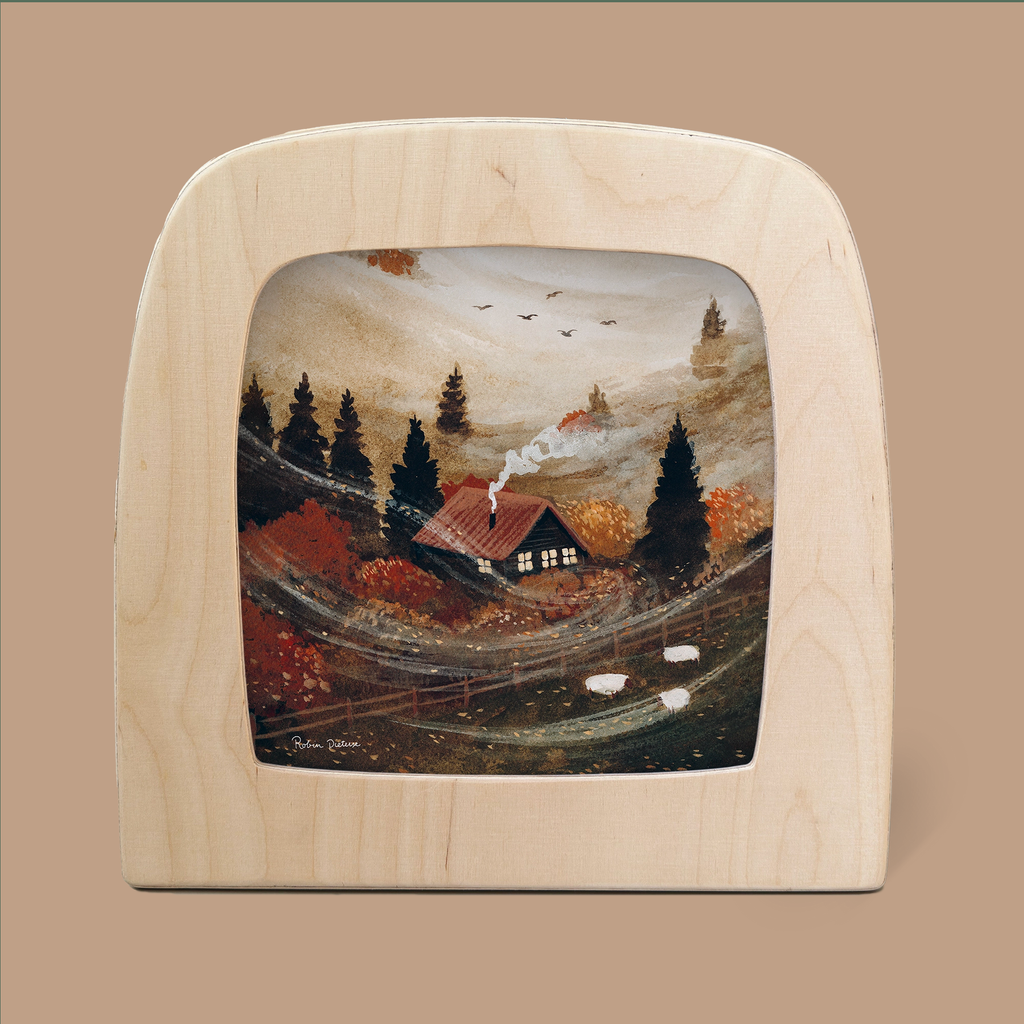 A cozy cabin nestled in a foggy, autumn landscape with vibrant orange and red trees. Smoke rises gently from the chimney like a Silhouette Only - October Cottage Silhouette for Toverlux Lamp, while two sheep graze nearby. Framed by a wooden arch, and exuding rustic charm, the scene feels enchanted.