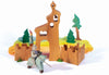 Experience imaginative play with the Ostheimer Blue Knight - Riding wooden toy set. This beautifully designed set features a handcrafted knight on horseback carrying a lance, a castle with turrets, vibrant greenery, and colorful fabric. The scene includes a figure in a wizard's hat next to a tower with a bell, surrounded by trees and pathways.