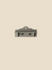 The Maileg Bonus Room Bathroom Set is a small gray wall-mounted shelf with two metal hooks, a decorative top edge, and a hanging hole—ideal as dollhouse accessories or for your Maileg House of Miniature. Shown on a plain beige background.