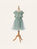 A display mannequin presents a child's Maileg Princess Blouse - Mint (Final Sale). The blouse, crafted from exclusive materials, features a ruffled top with short sleeves and a full tulle skirt. The mannequin stands on a wooden tripod base against a plain cream background, evoking a fairytale dream.