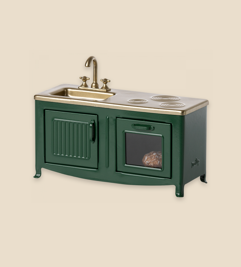 A Maileg Kitchen - Dark Green featuring a sink, faucet, stove, and an oven with a visible turkey inside, set against a neutral background.