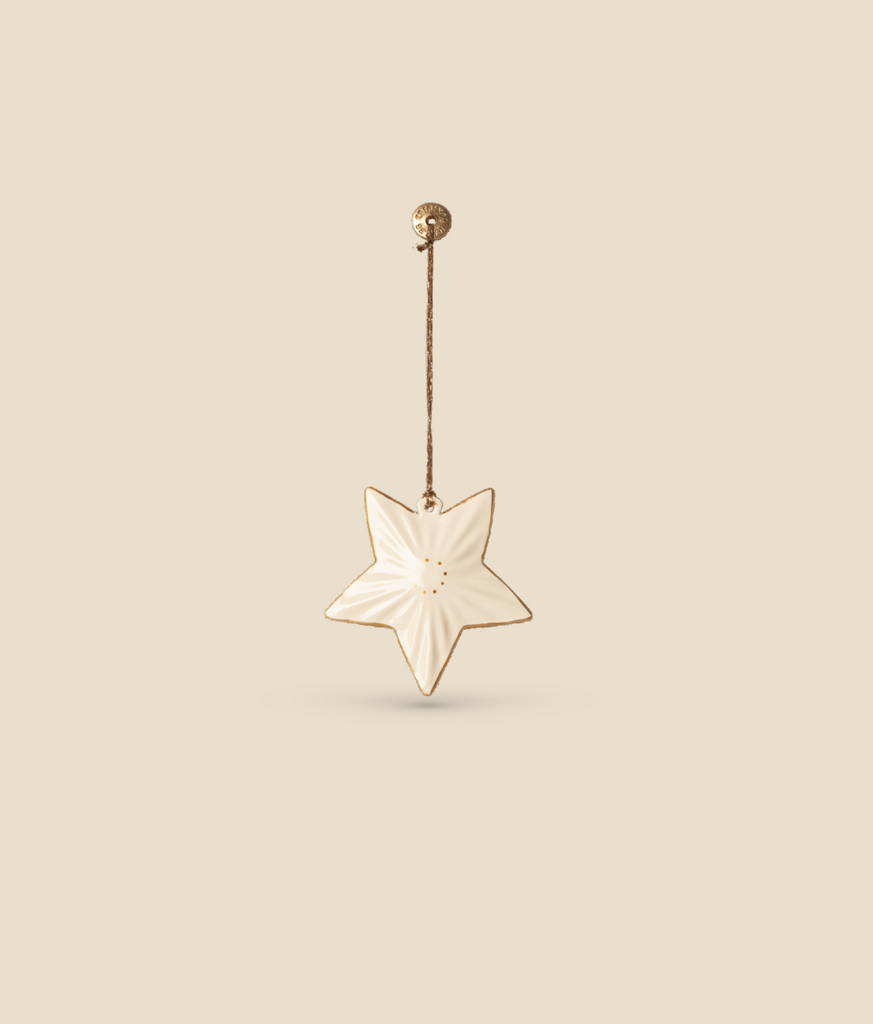 The Maileg Christmas Metal Ornament - Star is a beige, hand-painted star-shaped decoration adorned with subtle patterns. It hangs elegantly from a thin, brown string connected to a small, round beige knob. The solid beige background underscores its elegant simplicity, making it an ideal choice for adding timeless charm to any Christmas tree.