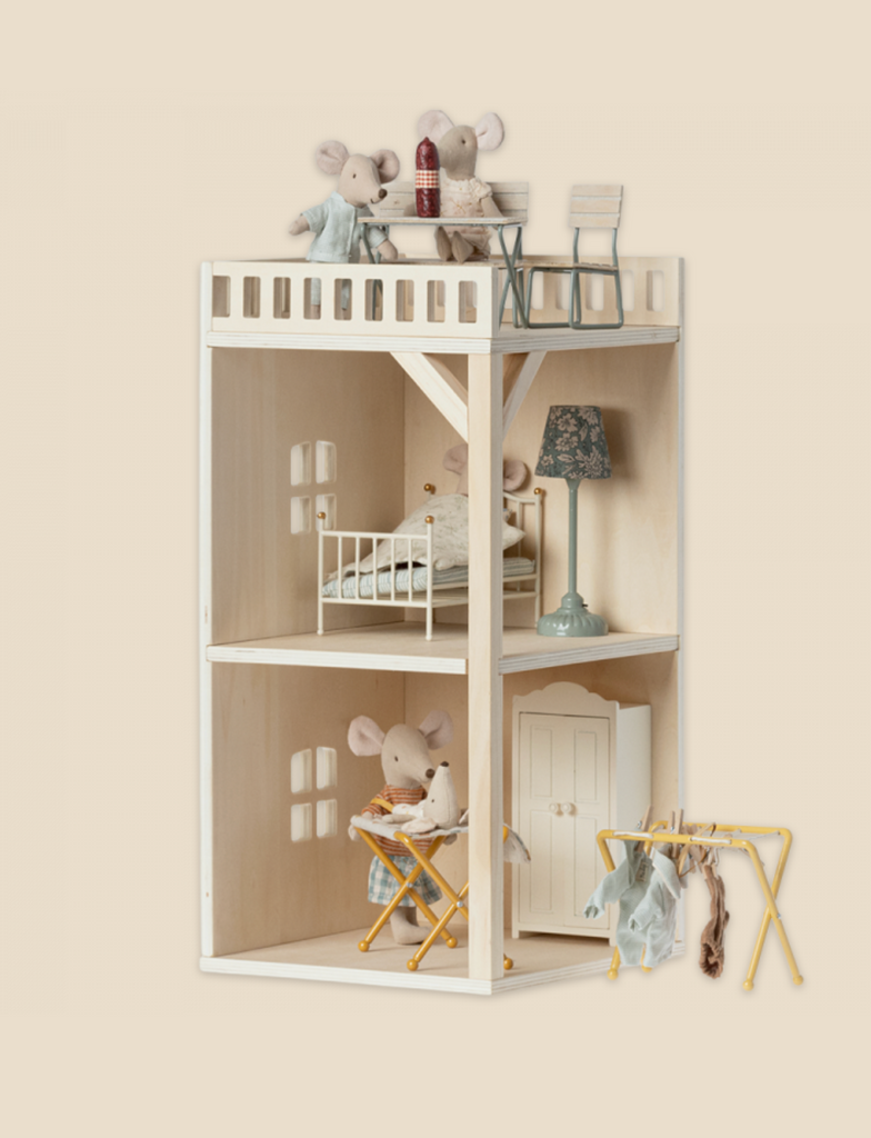 A charming wooden dollhouse featuring two levels; the top with a balcony and a bed, housing toy mice, and the lower level designed as a Maileg Farmhouse - Annex Bonus Room. Soft pastel tones and miniature furniture add to the cozy feel.