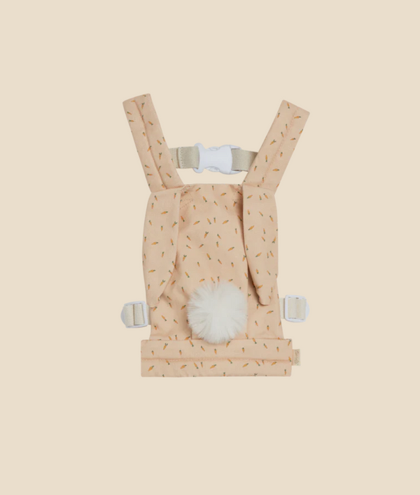 A plush Olli Ella x Odin Parker Dinkum Dolls Cottontail Carrier in peach with a pattern of tiny arrows, featuring adjustable straps and a soft white fur detail on the front.