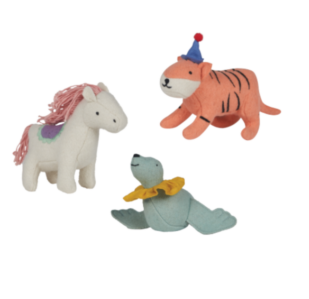 The Olli Ella Felt Holdie Circus Animals set includes three plush toy animals: a white horse with a pink mane and purple saddle, a tiger wearing a blue party hat with a red pom-pom, and a blue seal with a yellow ruffled collar. Perfect for imaginative play, each piece is carefully crafted from handmade wool blend.