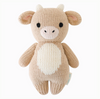 The Cuddle + Kind Baby Cow is a knitted plush with a light brown body, white belly, small black eyes, and fabric horns and ears. Made from soft Peruvian cotton yarn, it's perfect for hand-knit baby animal collectors. An authenticity tag is attached on its side.