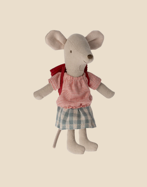A Maileg Big Sister With Backpack - Red, dressed in a red checkered shirt and blue plaid skirt with a red bow around the neck, stands upright against a beige background. Perfect as a kindergarten toy or an adorable tricycle accessory.