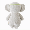 A Cuddle + Kind Baby Elephant, Blush Floral stuffed animal in the shape of an elephant, seen from the back. The elephant, made from heirloom-quality Peruvian cotton yarn, is light gray with large round ears and features a braided green and pink headband. A small label is attached to the right side of its body.