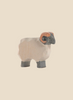 The Ostheimer Moorland Ram figurine features a light-colored body with dark legs, and a distinct dark face and ears. This handcrafted piece showcases visible wood grain and carved details, embodying the simplicity characteristic of Ostheimer wooden toys. It stands on a plain beige background, highlighting its use of sustainable materials.