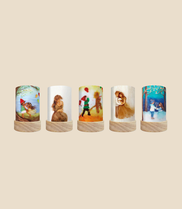 Five Toverlux Lantern Shades with wooden bases showcase a variety of whimsical illustrations, from children and teddy bears to vibrant backgrounds. Each lantern features unique, playful scenes with magical shades designed to create a cozy and imaginative ambiance as they celebrate the seasons. Delivery is approximately one week from purchase.