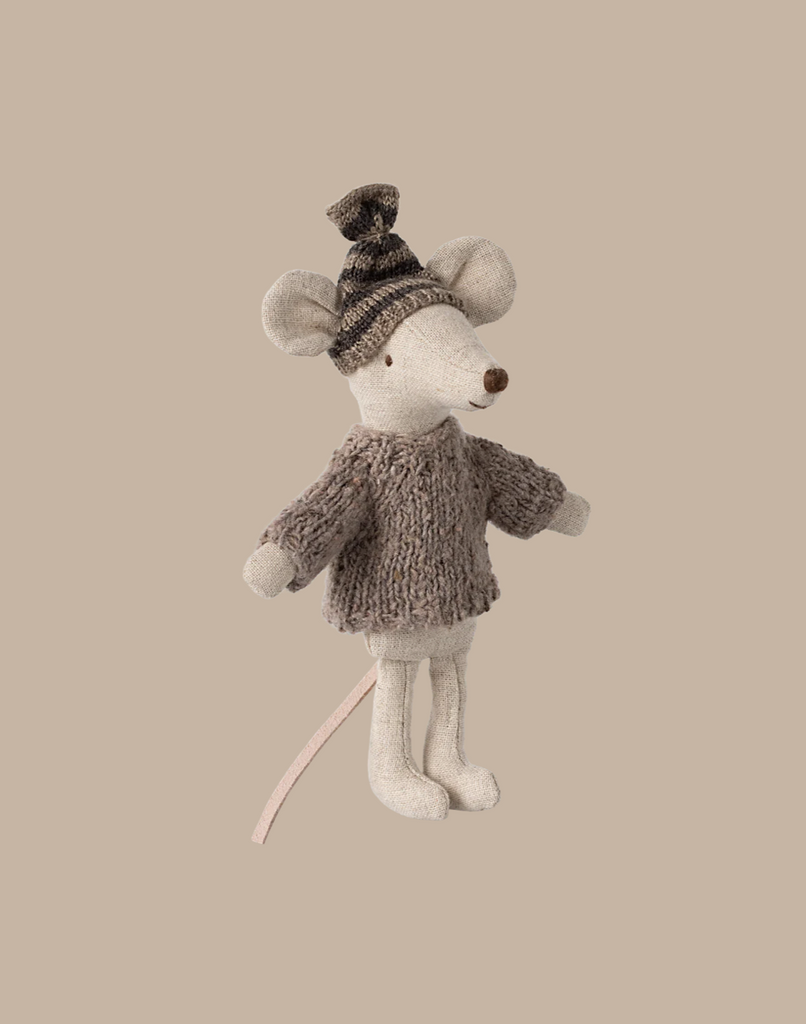 A charming big sister mouse toy, adorned in the Maileg Knitted sweater and Hat for Big Brother Mouse, stands against a plain beige background, highlighting her delightful winter accessories.