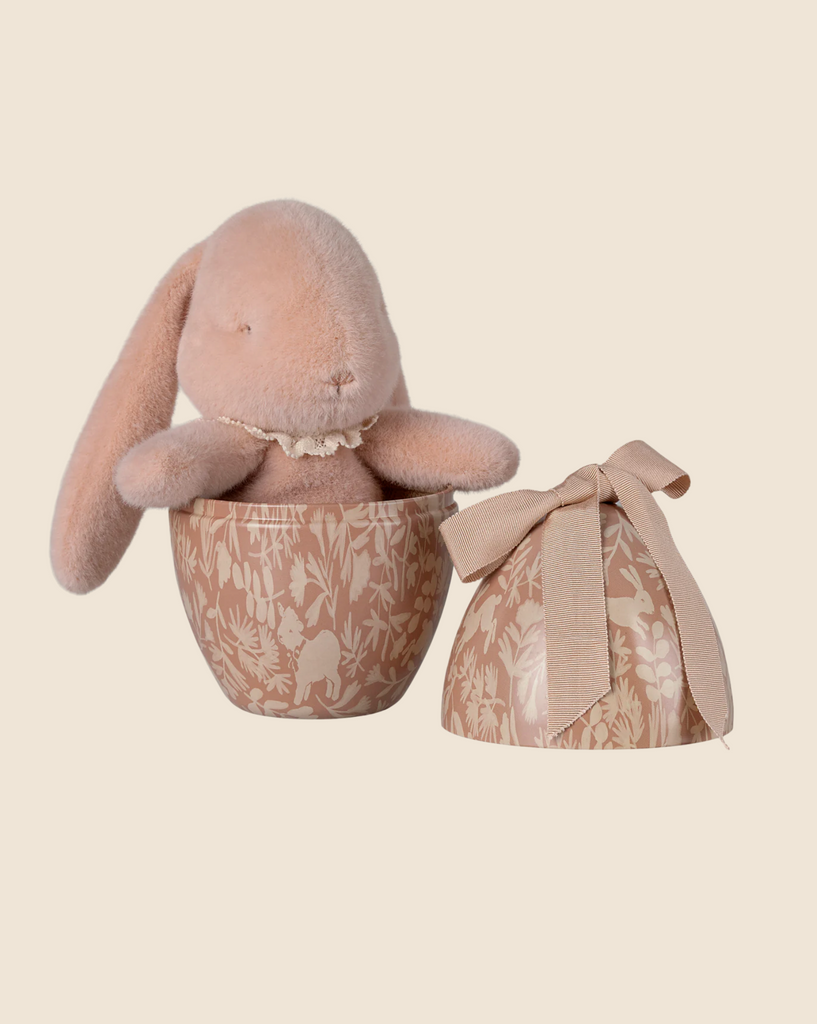 The PRE-ORDER: Maileg Easter Egg With Bunny - Powder features a plush bunny made from recycled polyester inside a brown floral-patterned, egg-shaped container with an open lid and ribbon bow. Ships in February.