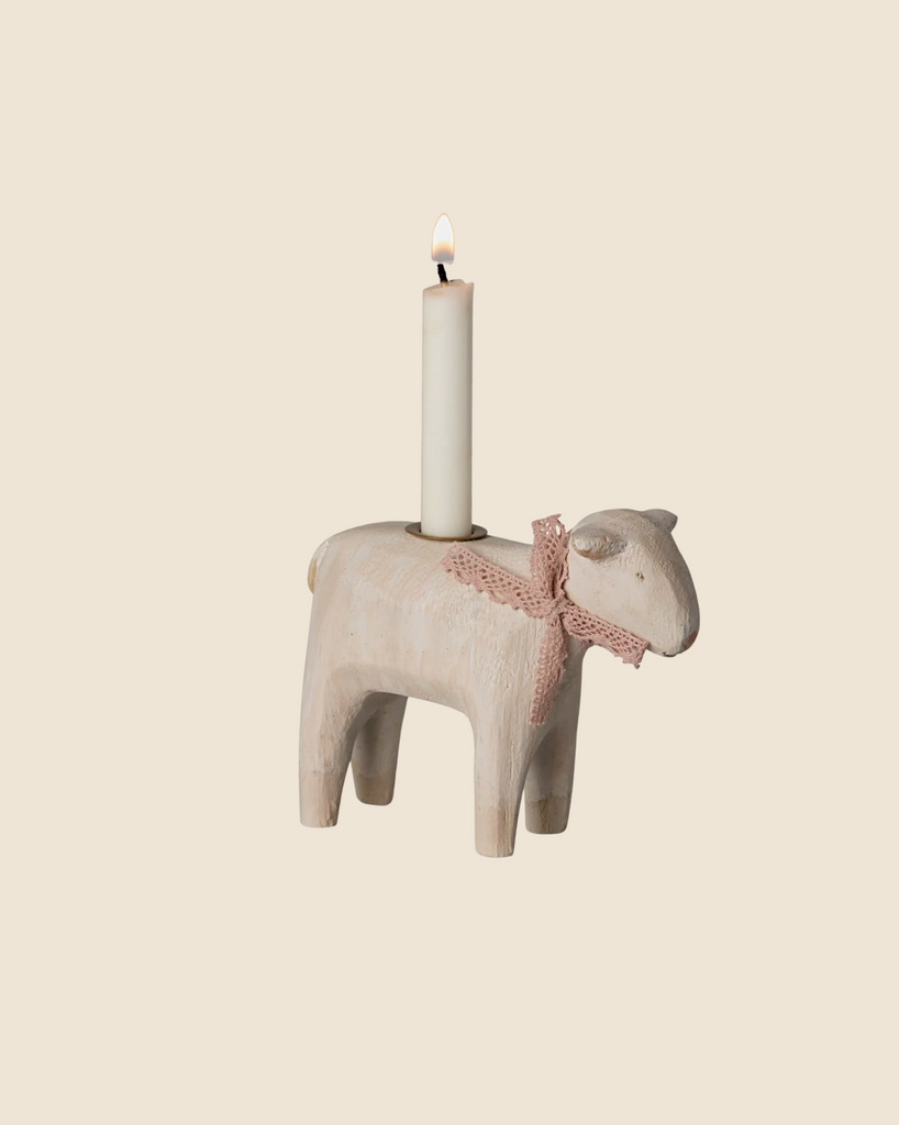 The Maileg Wooden Candle Holder - Rose Lamb, made of wood and featuring a pale pink ribbon around its neck, beautifully enhances any Easter table. This charming handmade piece holds a lit white candle on its back and ships in late January.