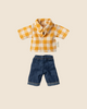 The PRE-ORDER Maileg Dad Mouse outfit, shipping late February, includes a charming yellow and white checkered shirt with a collar and dark blue denim shorts featuring rolled-up cuffs, displayed beautifully on a light beige background. Ideal accessories for your little friend!.